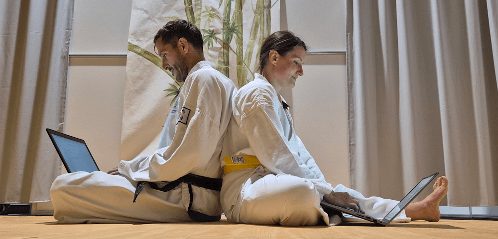 Das Sportanize-Gründerteam in Taekwondo-Doboks arbeitet gemeinsam am Laptop an der Vereinssoftware für Kampfsportschulen
